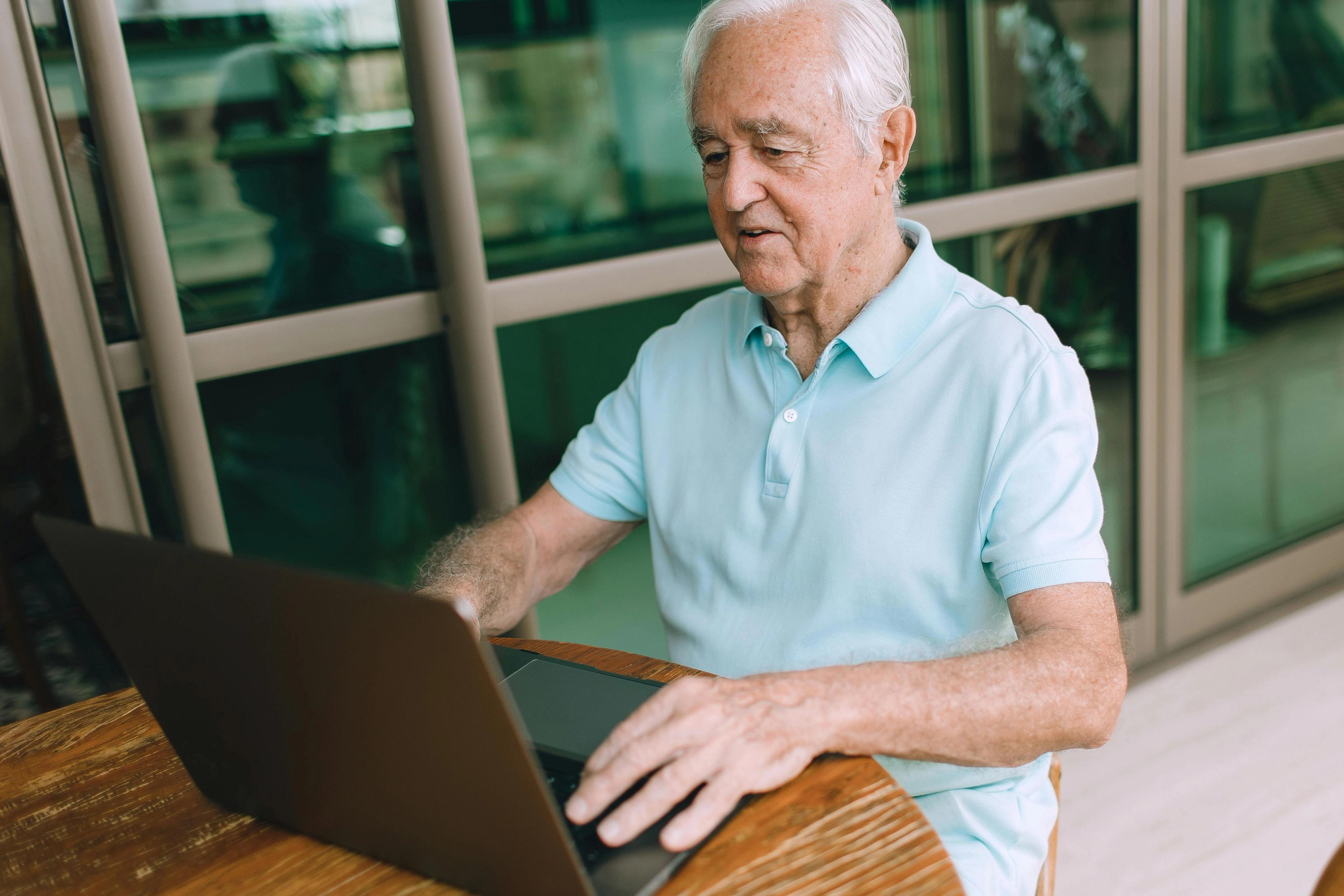 An older man writing a memoir on a laptop