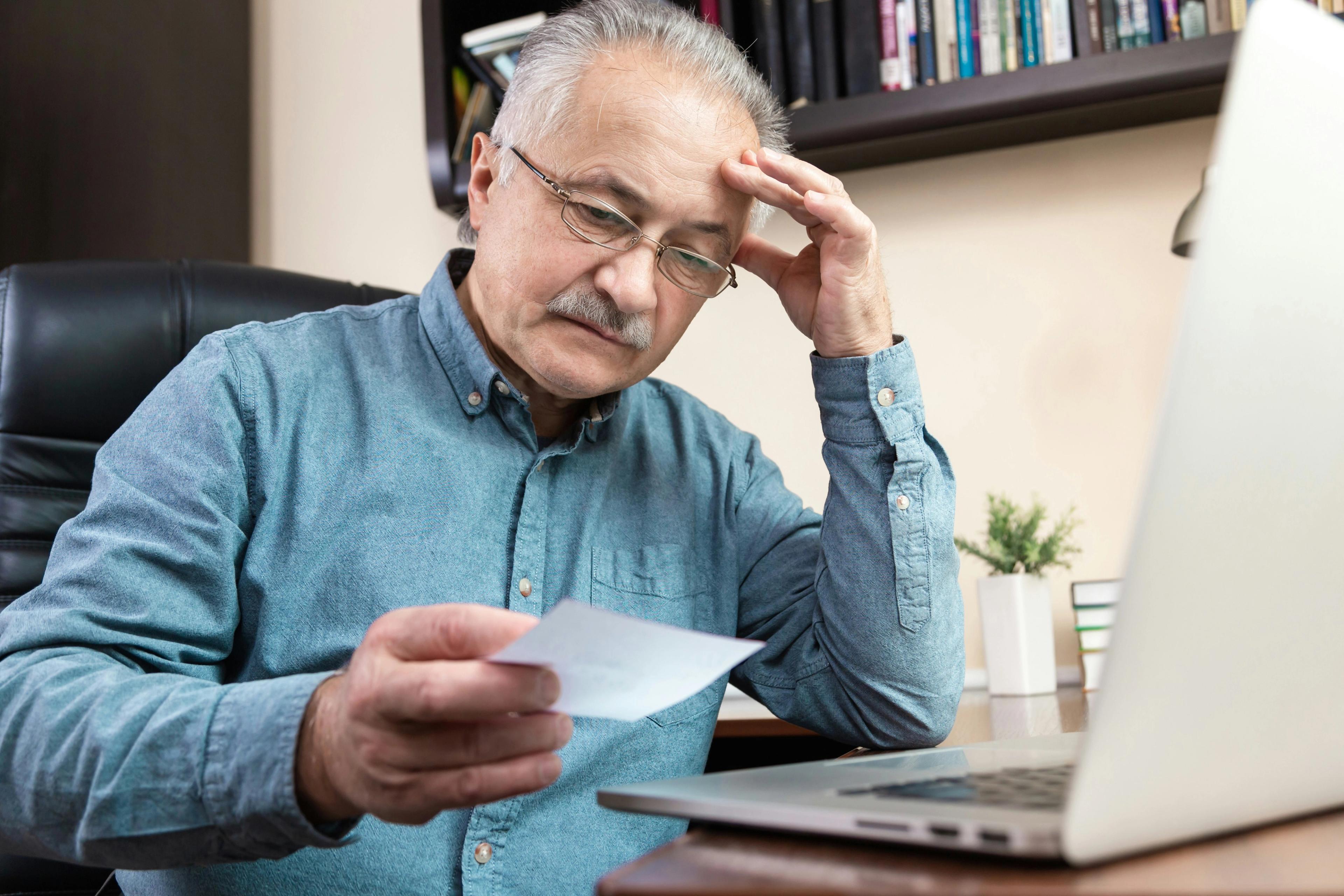 Man thinking what to include in his memoir with a note and laptop