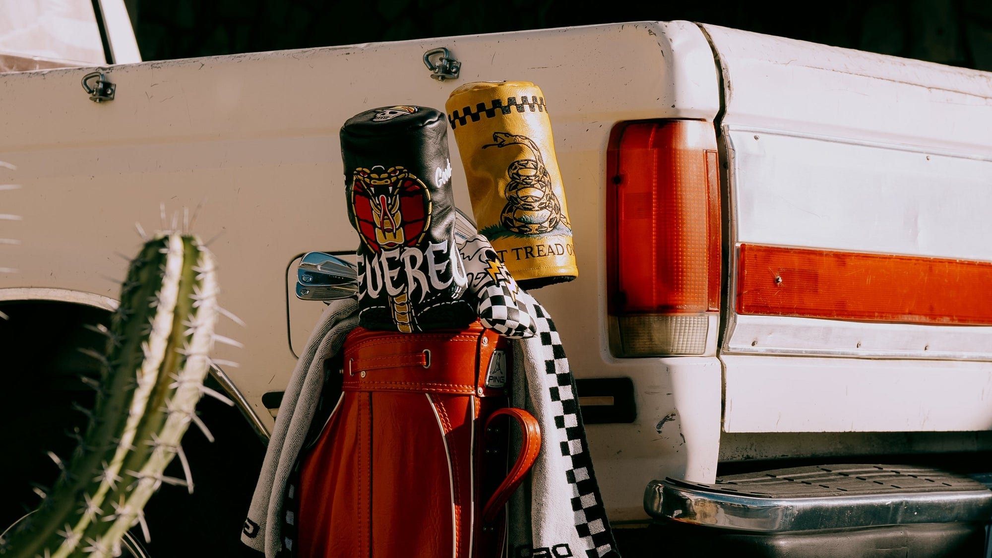 Devereux embroidered headcovers on a leather golf bag beside a vintage pickup, cactus in the foreground