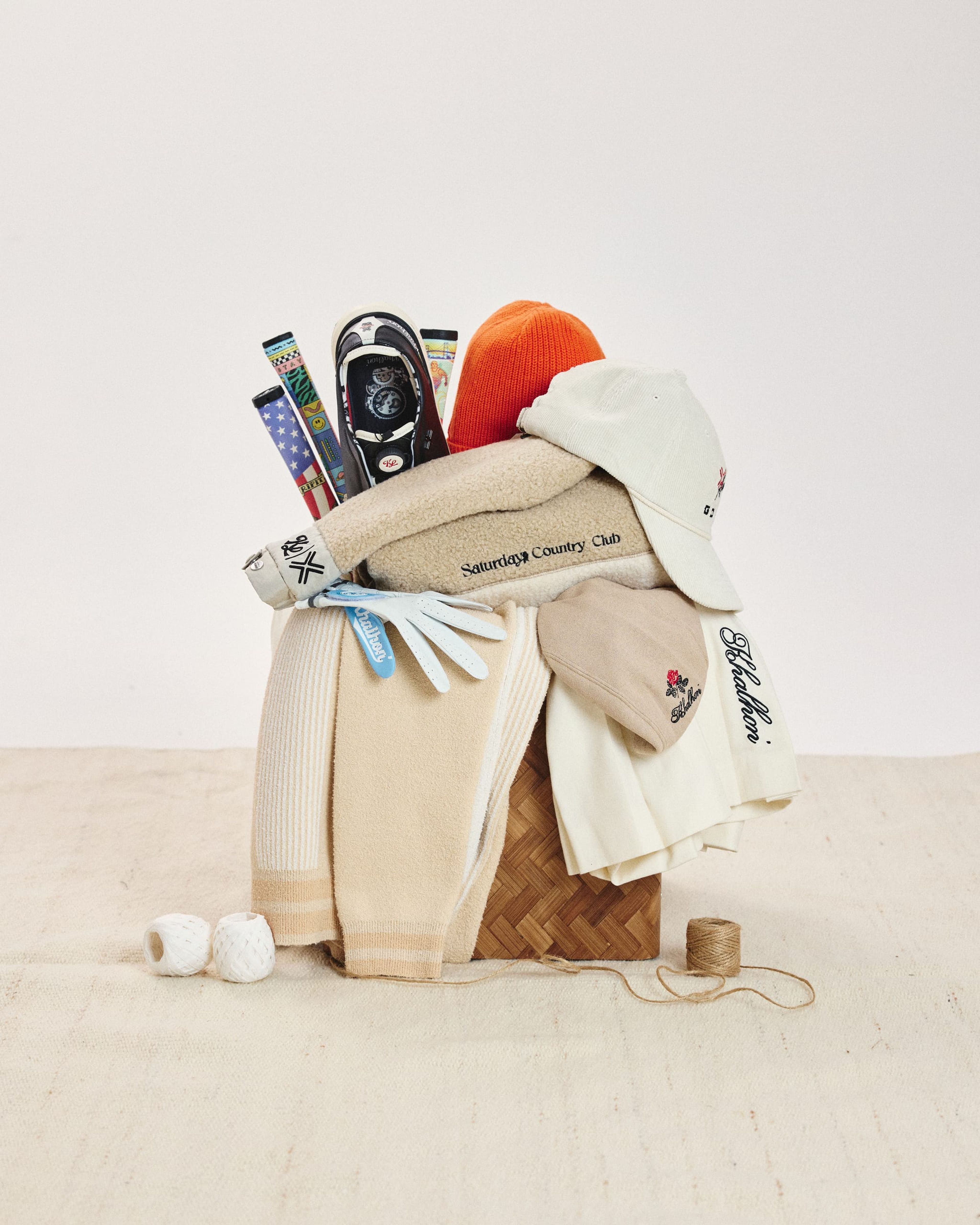 Khalhon still life: caps, knits, gloves, and grips stacked in a woven basket