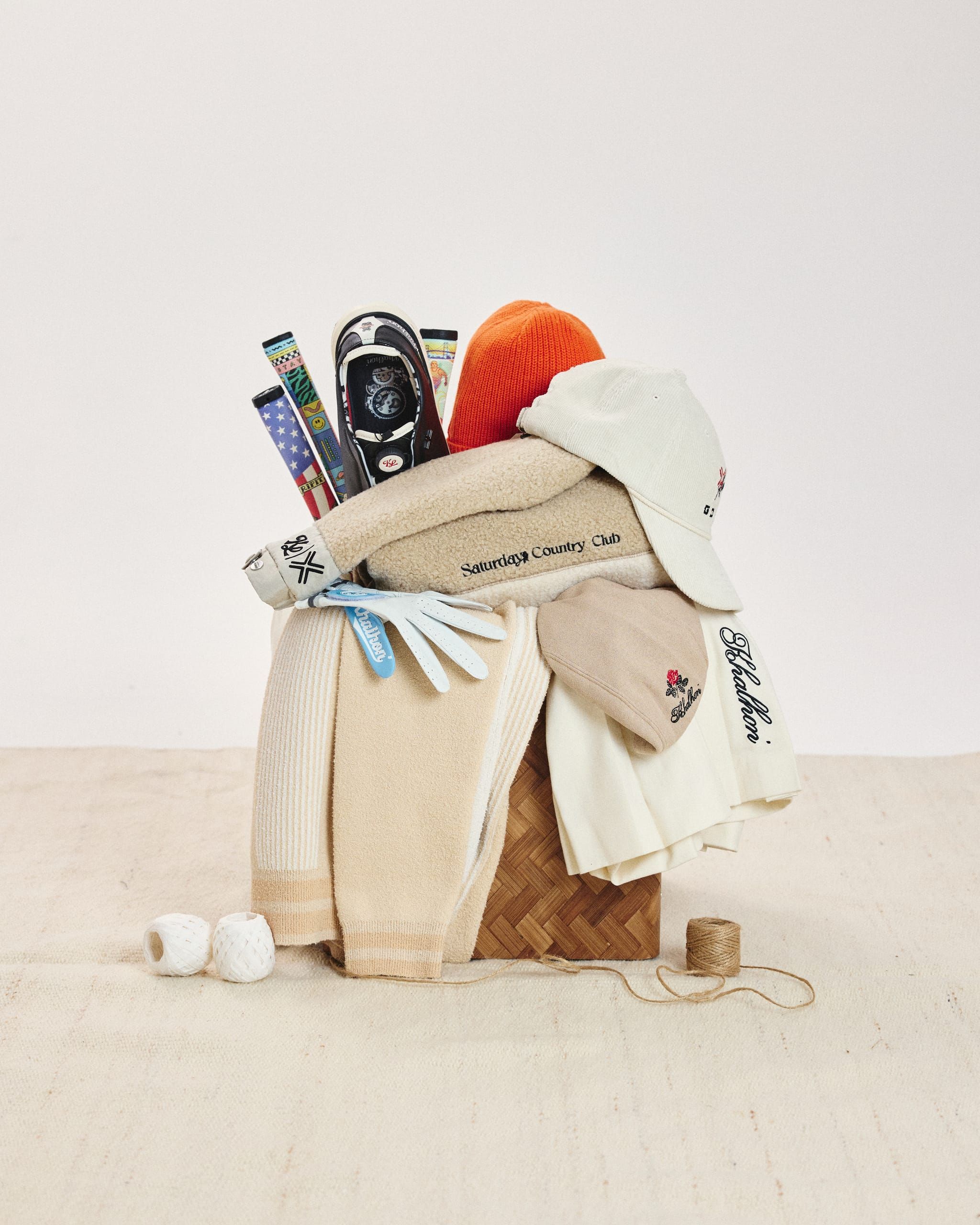 Khalhon still life: caps, knits, gloves, and grips stacked in a woven basket