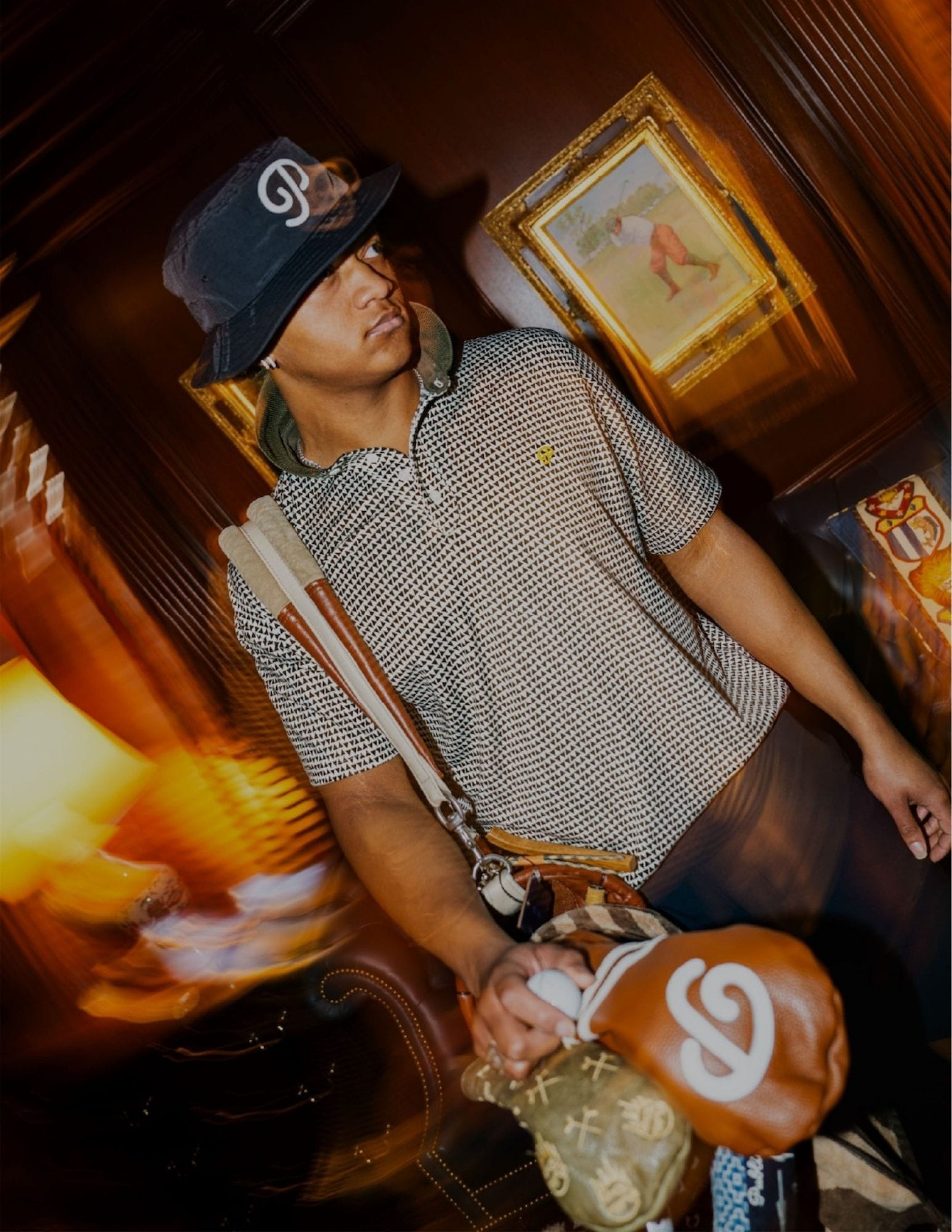 Public Drip campaign: golfer in a houndstooth polo and bucket hat carrying a vintage golf bag through a wood-panelled clubhouse