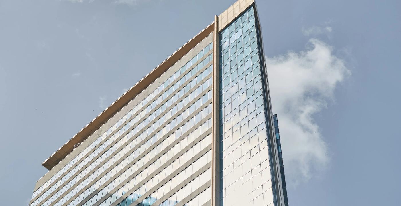 A modern glass-walled commercial office building against a clear blue sky.