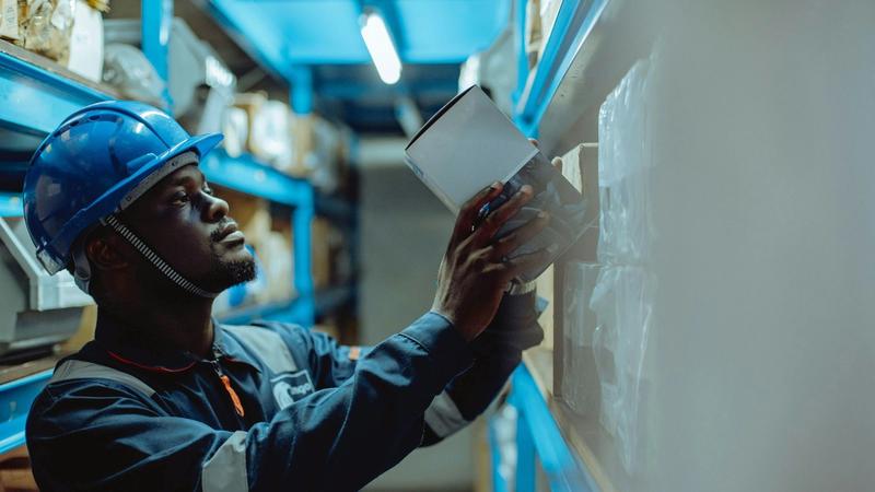 A worker in a hard hat examines a document while reviewing plans on a job site.