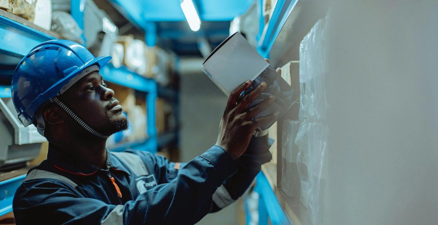 A worker in a hard hat examines a document while reviewing plans on a job site.