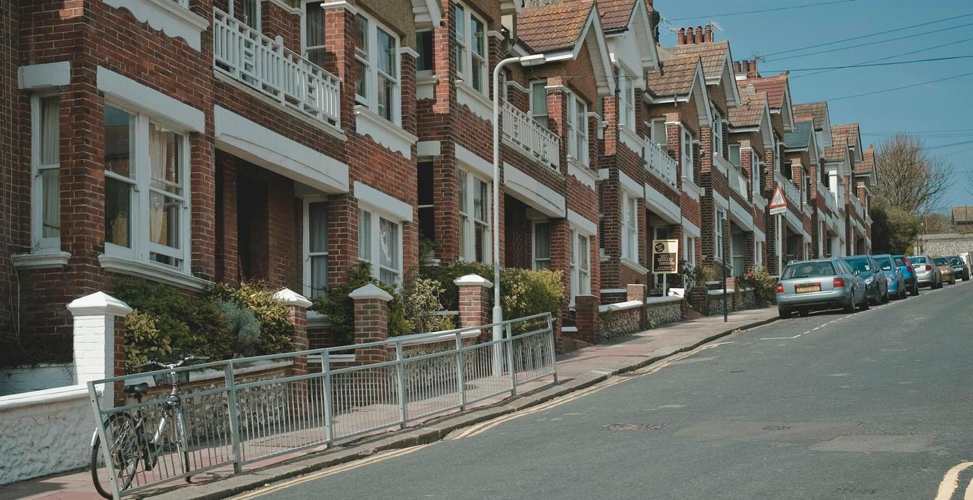 A residential street in Brighton, UK: a row of brick and rendered houses beside the road in daytime.