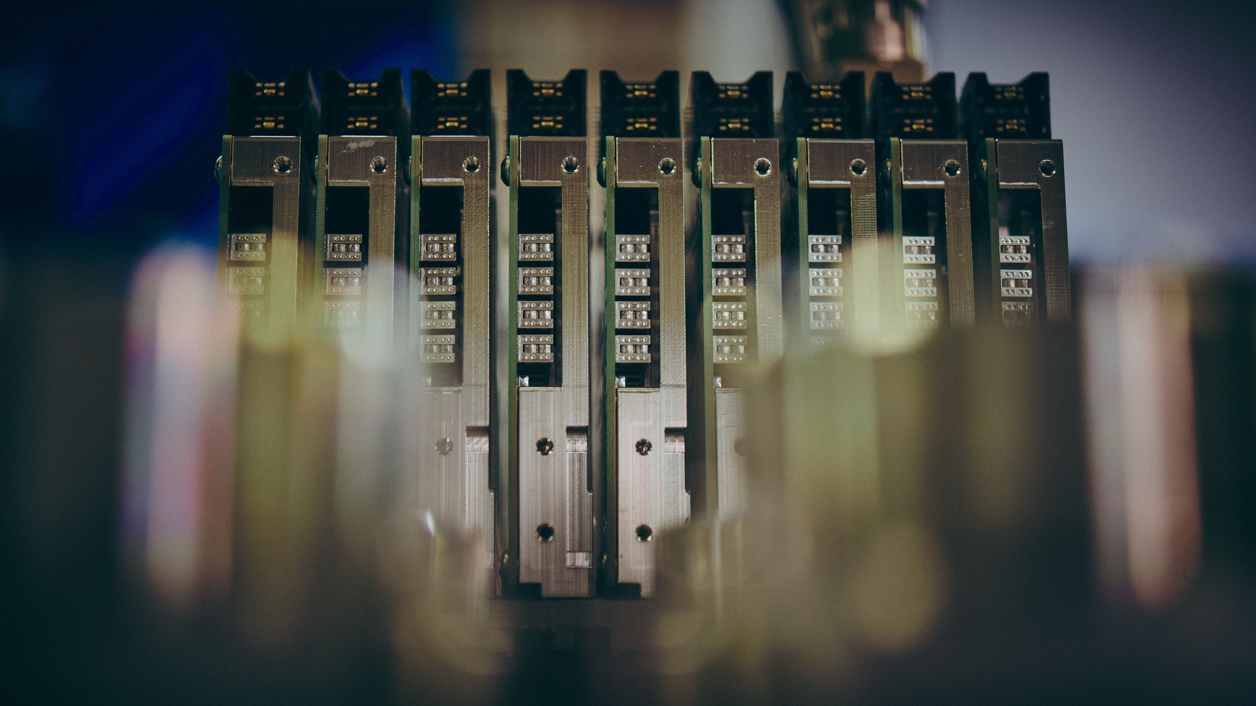 A row of stainless steel electrical modules seated in a rack, lit in cool blue