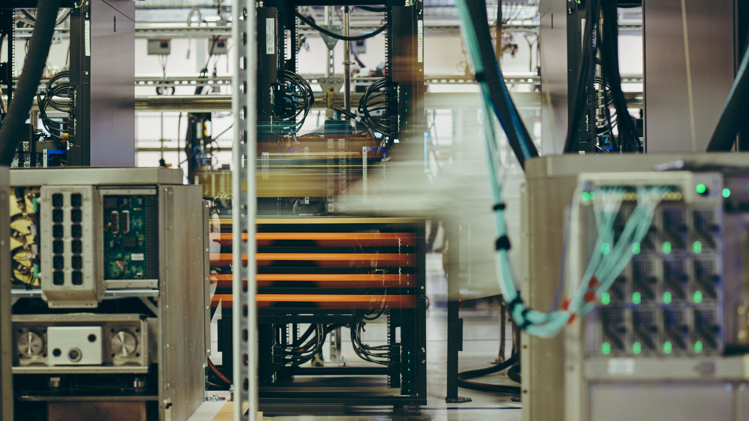 Wide view of the plant interior: equipment racks, orange power bars and a control panel of green indicator lights