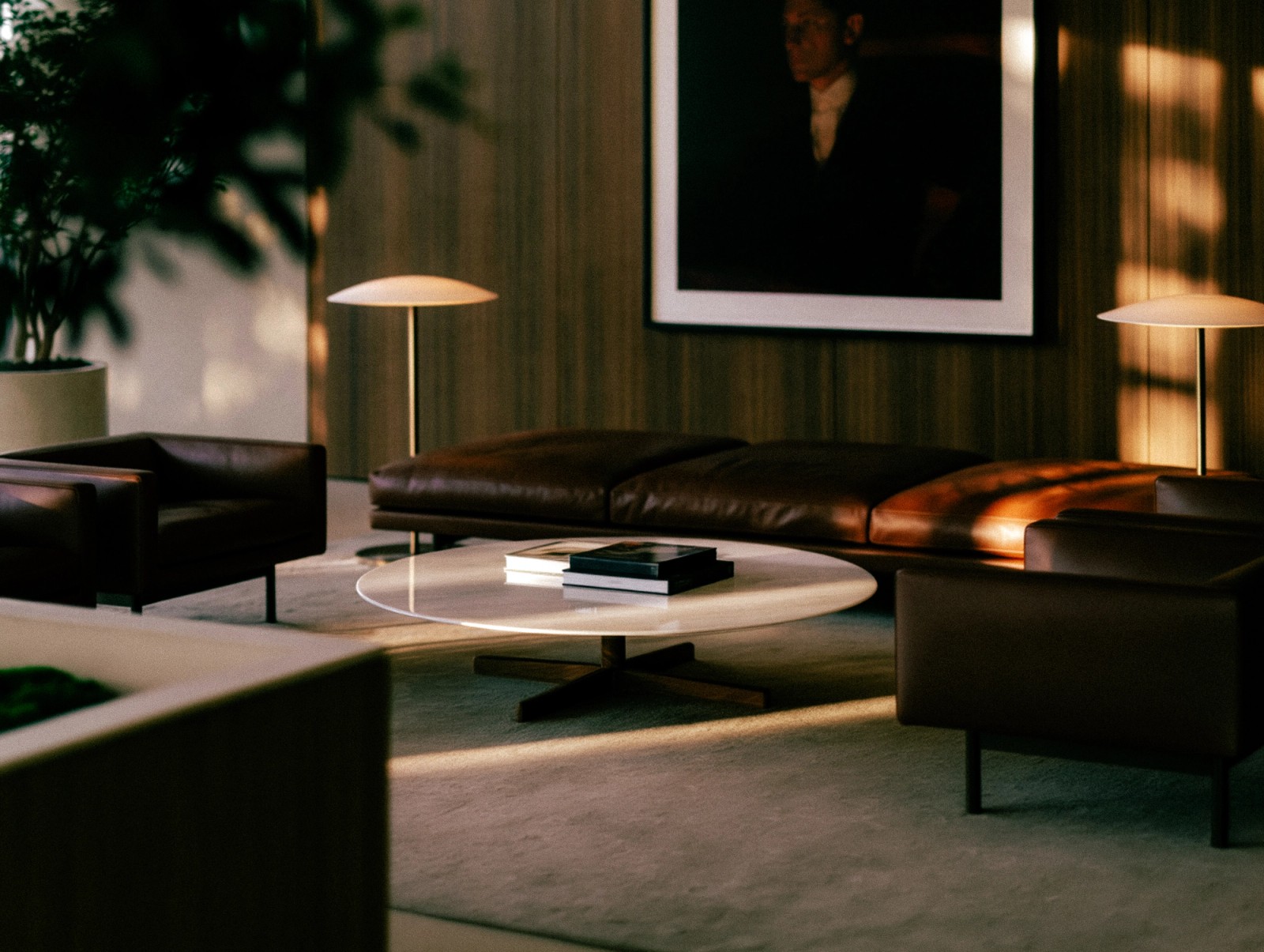 A modern lounge with brown leather furniture, a white coffee table, and warm sunlight streaming across.