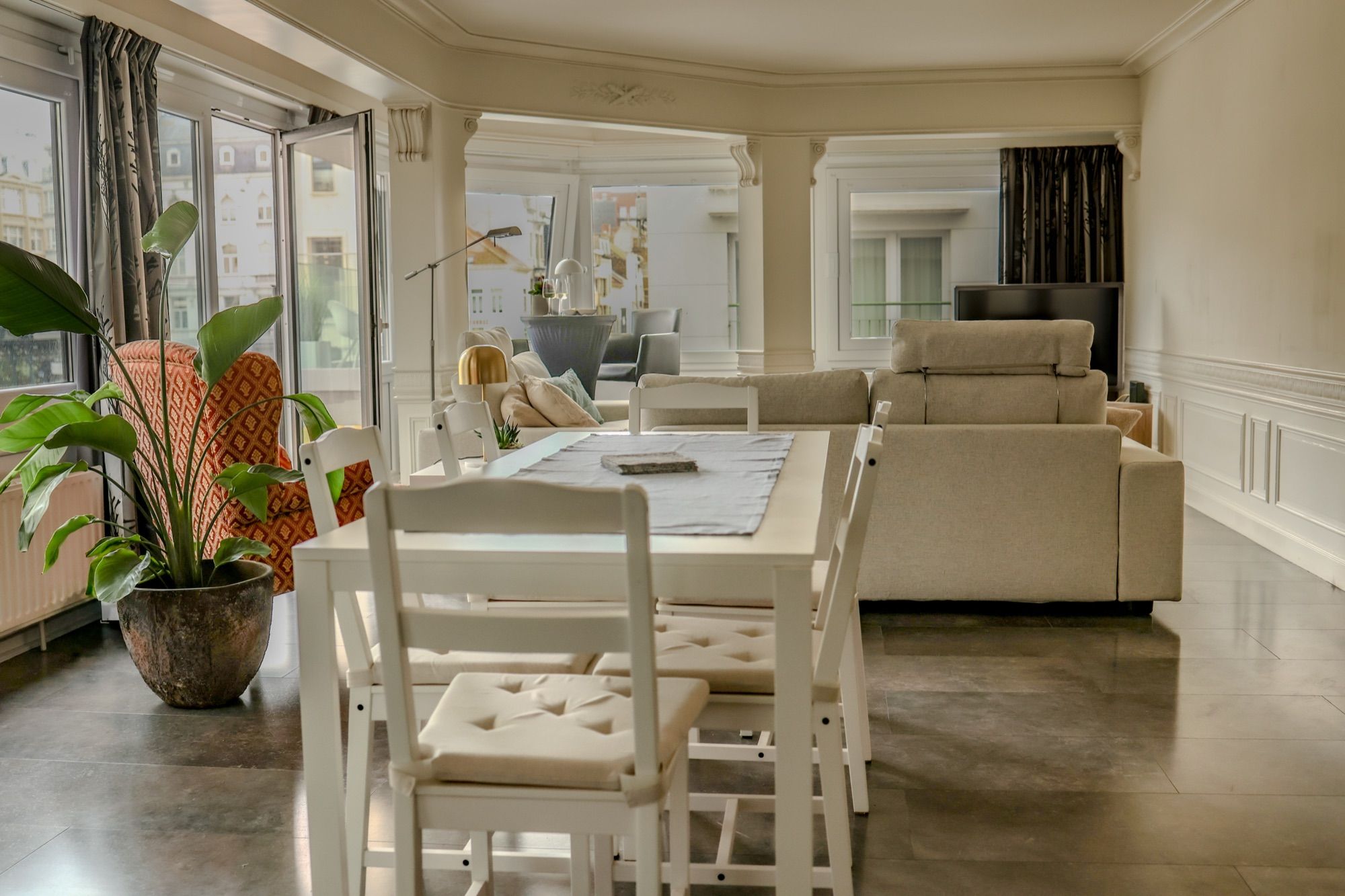 De witte eettafel met zes stoelen, naast de zithoek