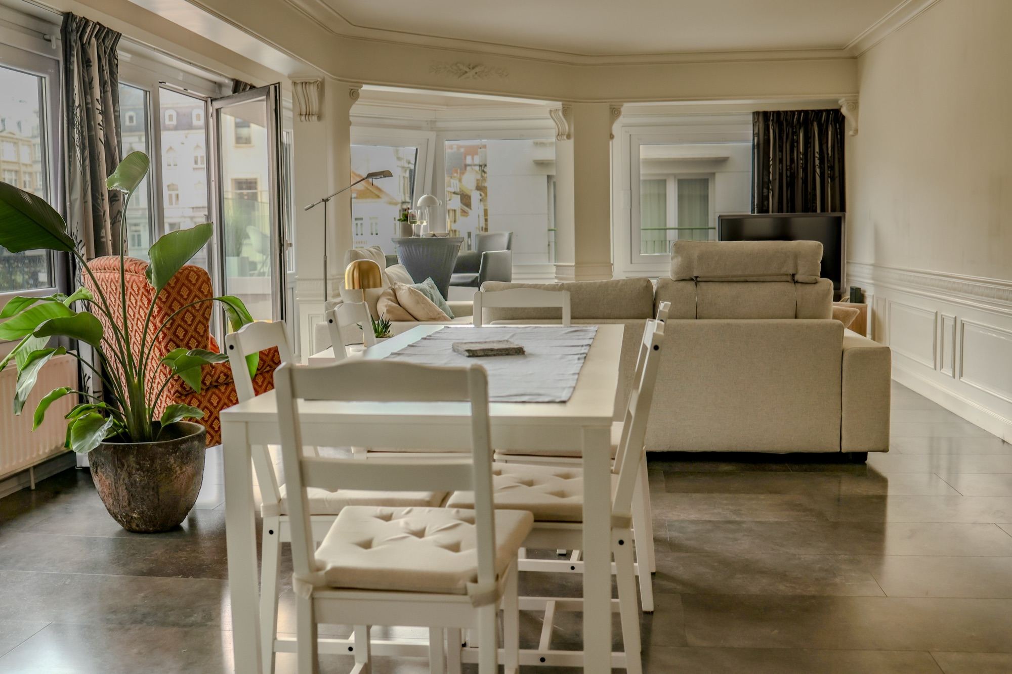 De witte eettafel met zes stoelen, naast de zithoek