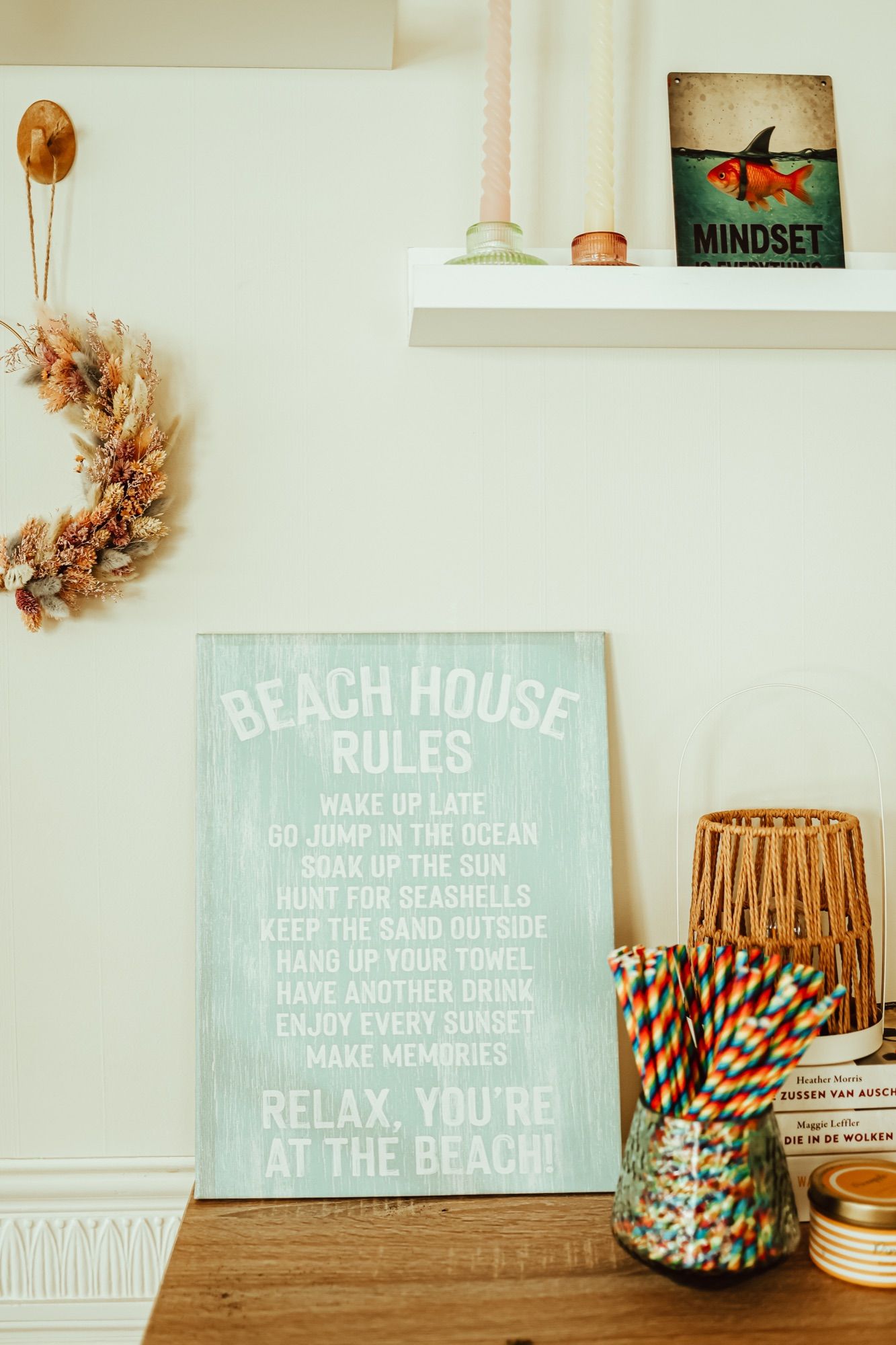 Een houten bord met 'Beach House Rules' tegen de wand