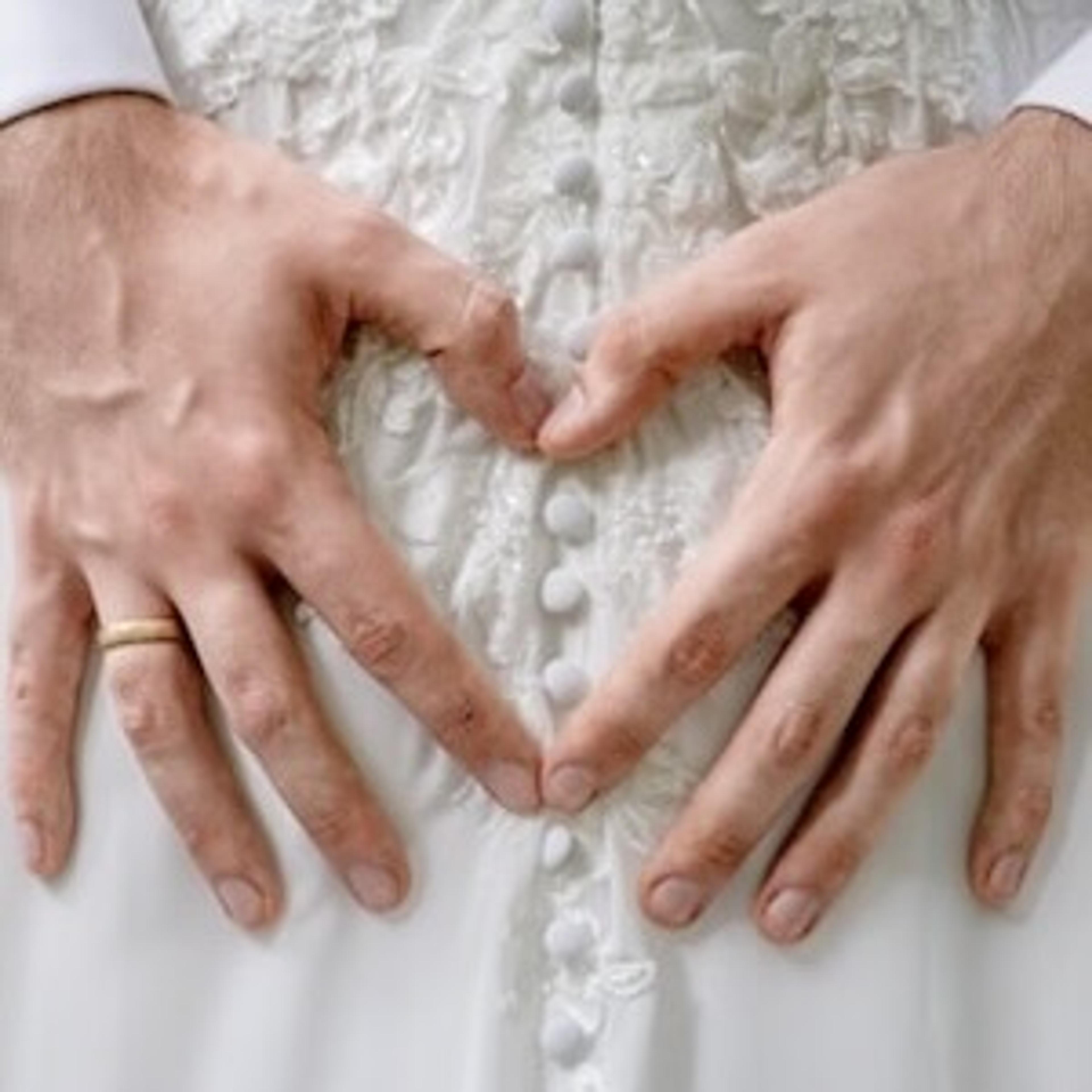 Hände formen ein Herz auf einem Brautkleid — Momentaufnahme vom Hochzeitstag