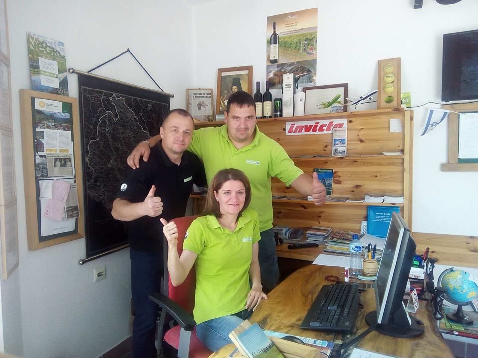 Przyjazny zespół Sport Turist, dwóch mężczyzn i kobieta, uśmiechający się i pokazujący kciuki w górę w swoim biurze.