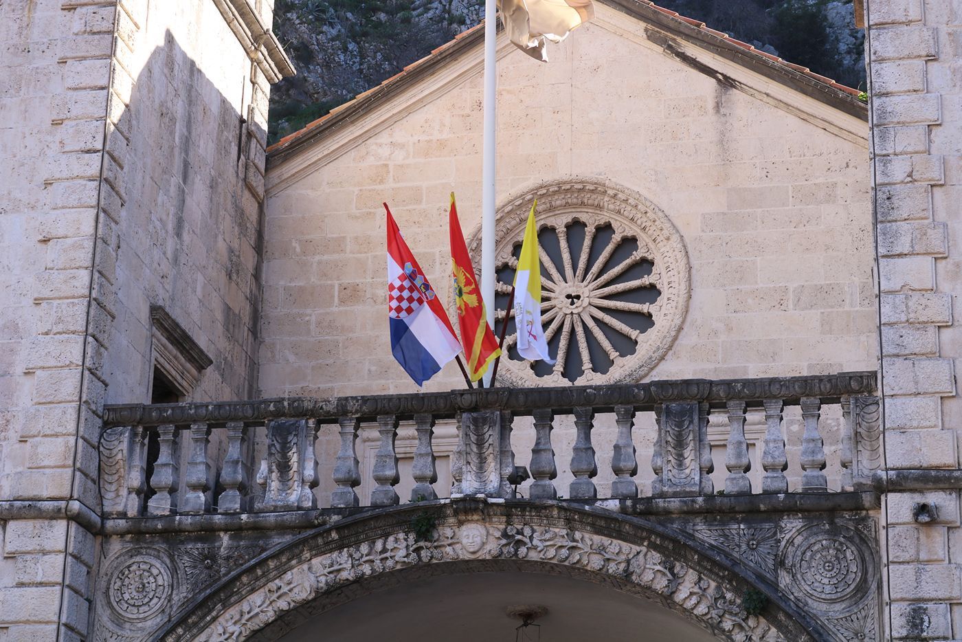 A close-up of the ornate rose window and balcony on the facade of St. Tryphon's Cathedral in Kotor.