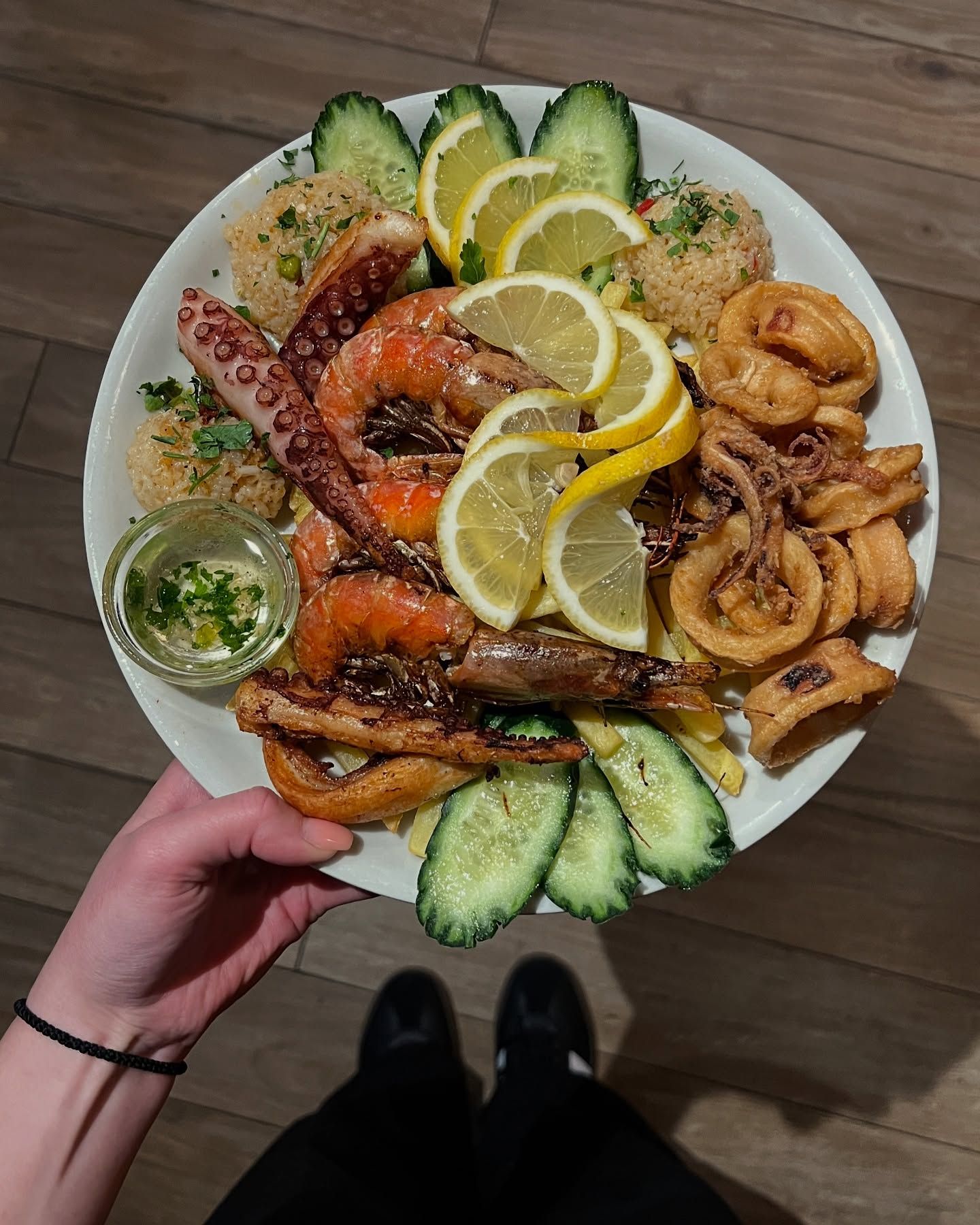 A beautifully presented platter of grilled and fried seafood, including octopus, shrimp, and calamari, garnished with lemon and cucumber.