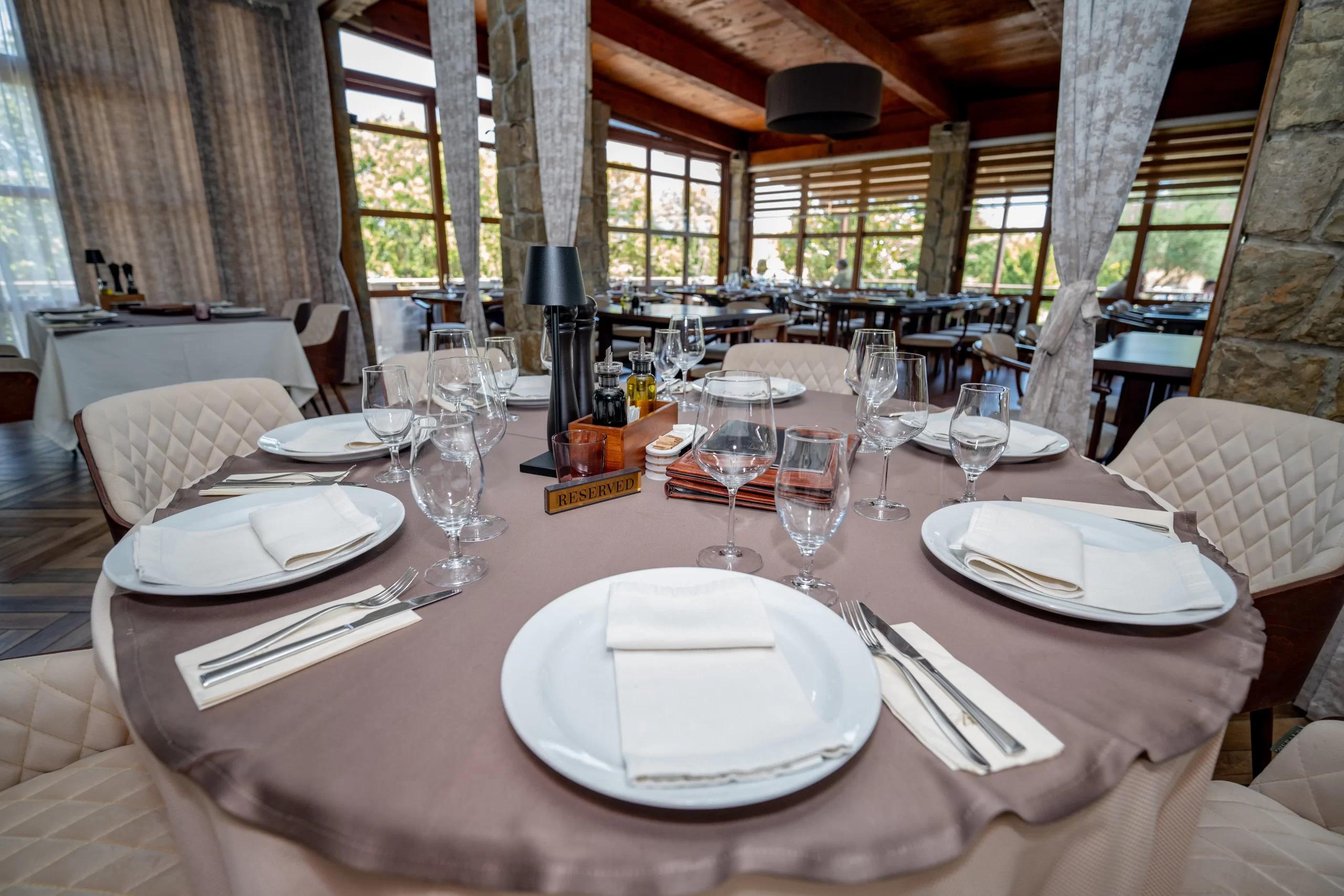 An elegantly set round dining table with a 'Reserved' sign at the Hotel Aria restaurant, ready for guests.
