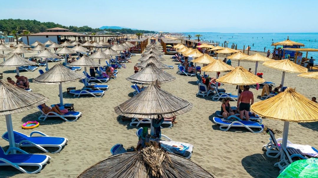 Rows of thatched umbrellas and sunbeds stretching into the distance on the vast sandy expanse of Velika Plaža in Ulcinj.