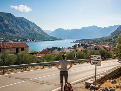 Traveler from behind looking at a road sign pointing to Kotor and Perast, with a stunning view of the Bay of Kotor in the background.
