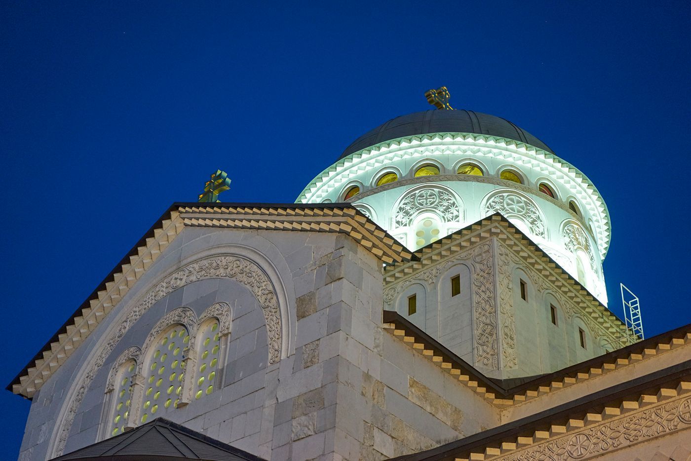 A close-up of the Cathedral's illuminated dome at night, showcasing intricate architectural details against the dark blue sky.