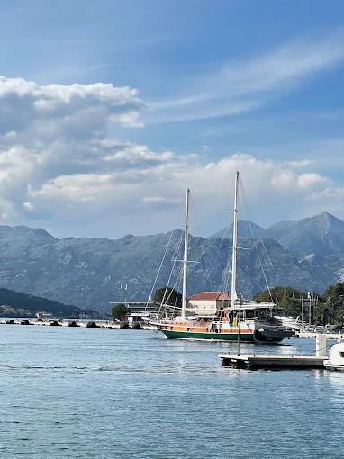 Stunning view of the Bay of Kotor from Restaurant Galion, showing a sailboat on the calm waters with the mountains in the background.