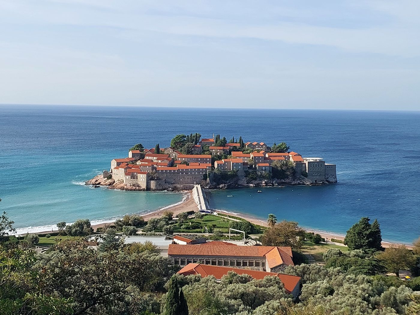A wide panoramic view of the Sveti Stefan resort island and the surrounding Budva Riviera coastline.