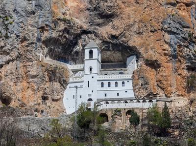 The dazzling white Ostrog Monastery, built directly into the vertical face of a rocky cliff in Montenegro.