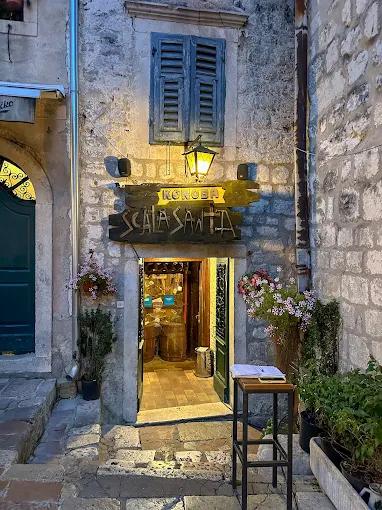 Rustic stone facade of the Konoba Scala Santa restaurant at night, with an illuminated wooden sign and a welcoming entrance.
