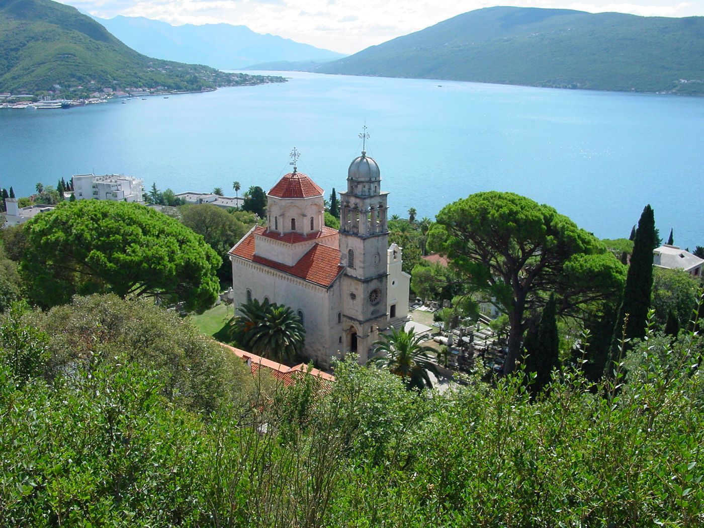 The Savina Monastery complex nestled in lush greenery, overlooking the wide blue expanse of the Bay of Kotor.