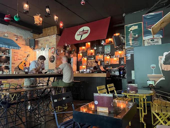 The cozy interior of Street Bar, with patrons sitting at the bar and a warm, inviting ambiance with vintage decor.