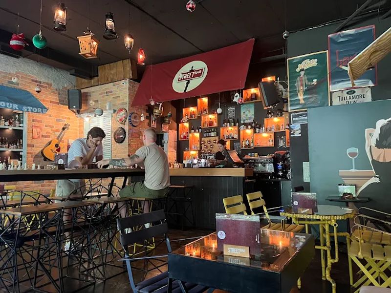 The cozy interior of Street Bar, with patrons sitting at the bar and a warm, inviting ambiance with vintage decor.