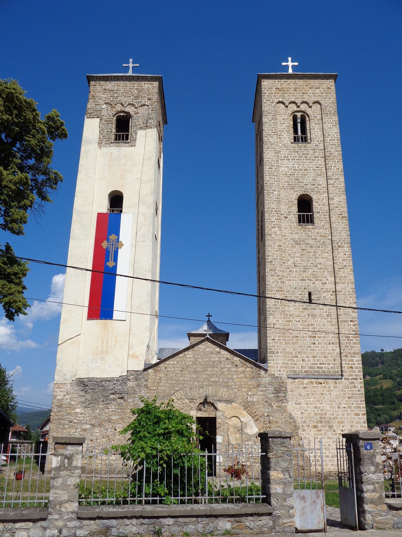 The historic Church of Saints Peter and Paul in Bijelo Polje, with its iconic twin bell towers against a blue sky.