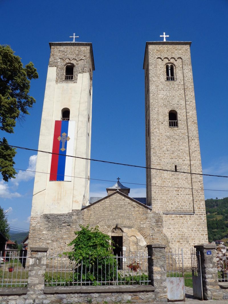 The historic Church of Saints Peter and Paul in Bijelo Polje, with its iconic twin bell towers against a blue sky.