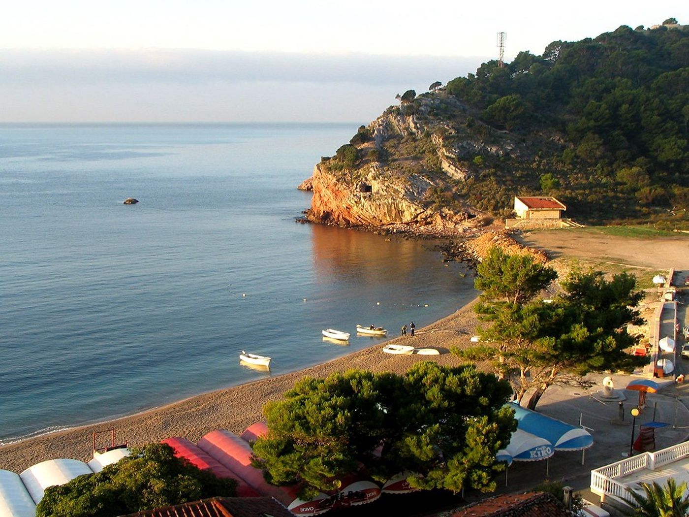 A tranquil cove at the end of Sutomore Beach, with small boats resting on the shore at sunset.