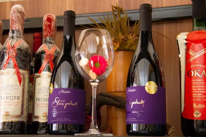 Close-up of 'Stari Podrum' wine bottles from Plantaže arranged on a shelf, next to a decorated wine glass.