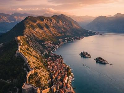 Aerial view of the walled city of Kotor, Montenegro, at sunset, with the fortress walls climbing the mountain and the islands in the Bay of Kotor.