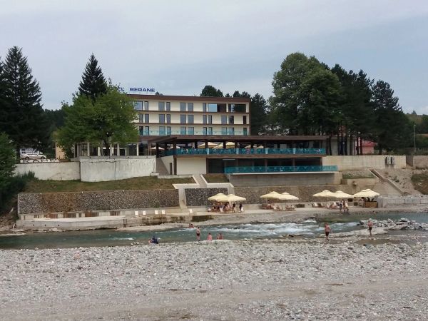 Moderni Hotel Berane u Crnoj Gori, smješten na obali rijeke Lim, sa uređenom plažom sa suncobranima i ljudima koji uživaju u vodi