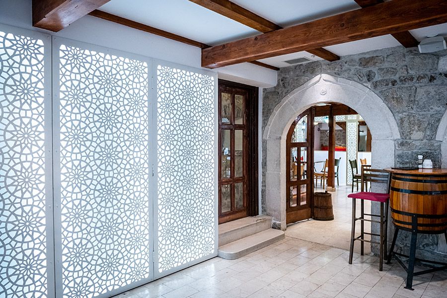 A view of the interior architecture of Konoba Lanterna, showing a stone archway and modern, backlit decorative panels.