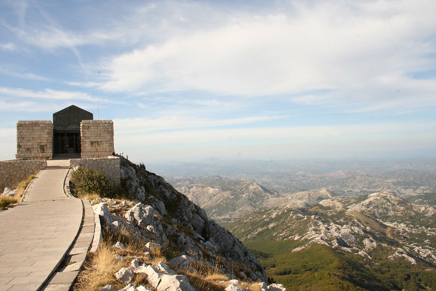 The Njegoš Mausoleum perched on the rocky summit of Mount Lovćen, overlooking a vast mountainous landscape.