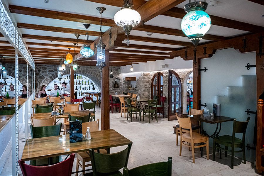 The warm and inviting interior of Konoba Lanterna, with wooden tables, stone walls, and ornate hanging lamps.