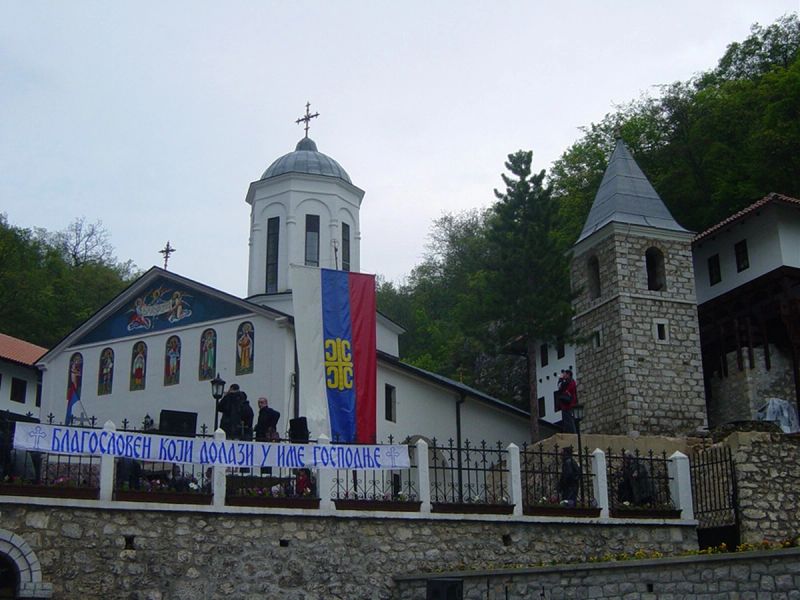 The white church of the Holy Trinity Monastery in Pljevlja, decorated with mosaics and banners for a celebration.
