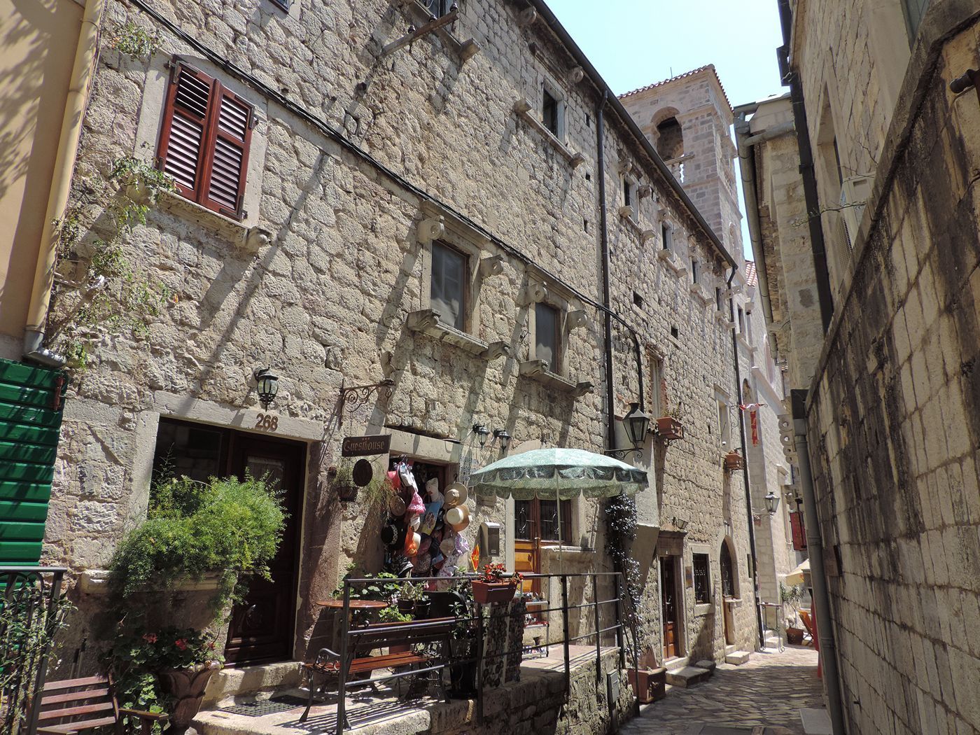 A narrow, charming stone alleyway in the labyrinthine Old Town of Kotor, with shops and residences.