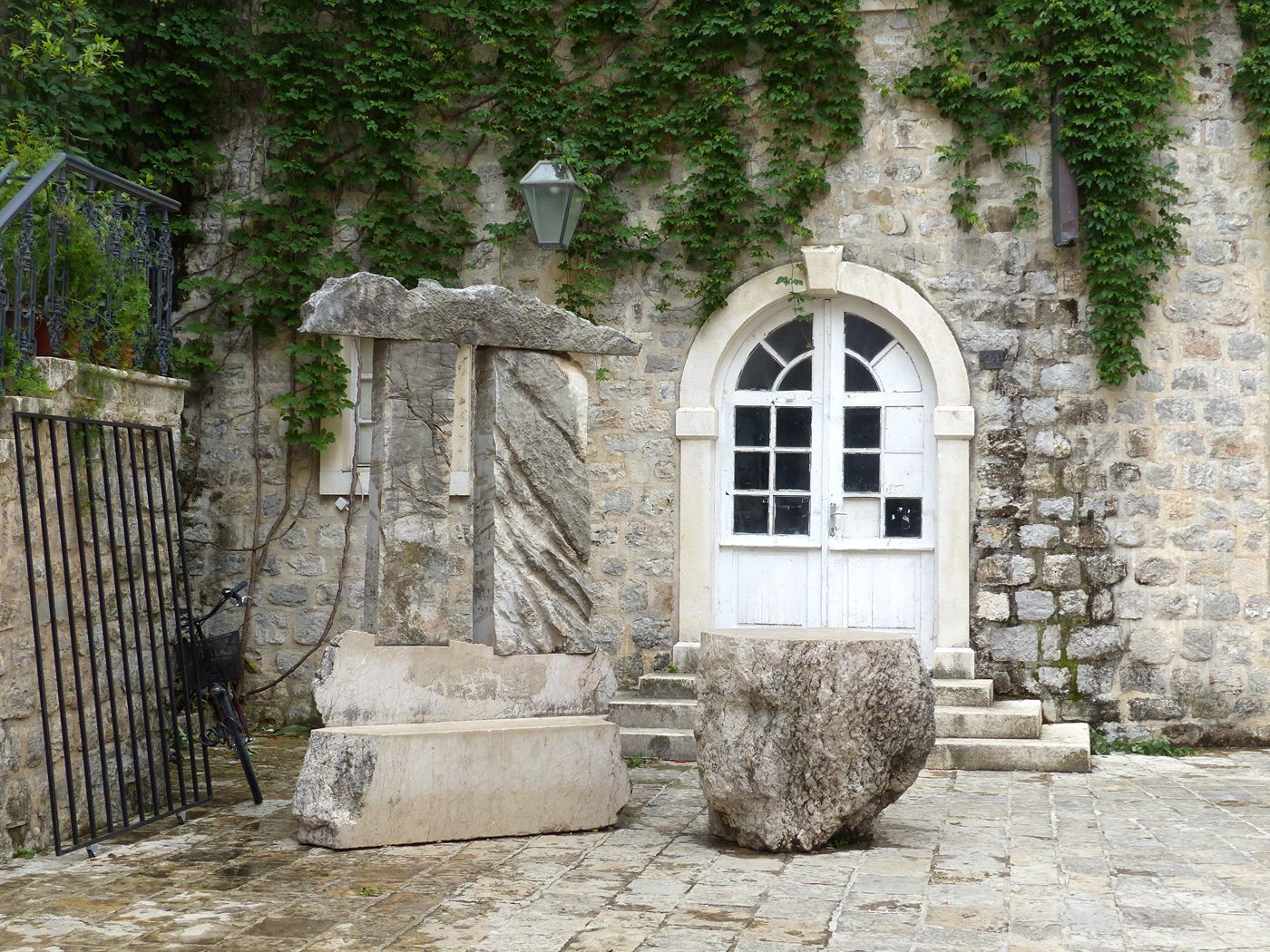 布德瓦旧城区一个安静的石头广场，有一座现代石雕和一堵常春藤覆盖的墙。