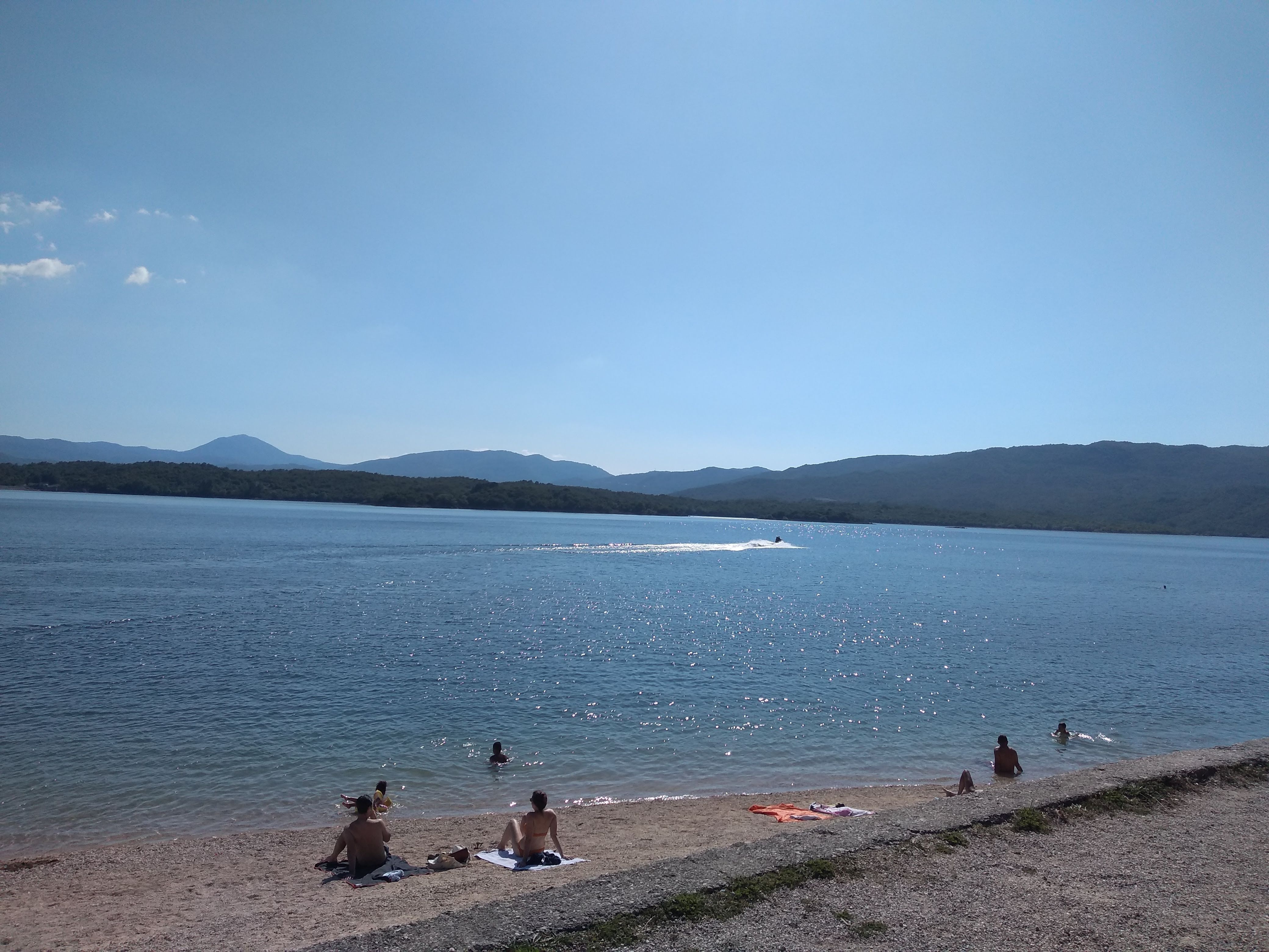 People swimming and a jet ski on the sparkling blue water of Lake Krupac on a sunny day.