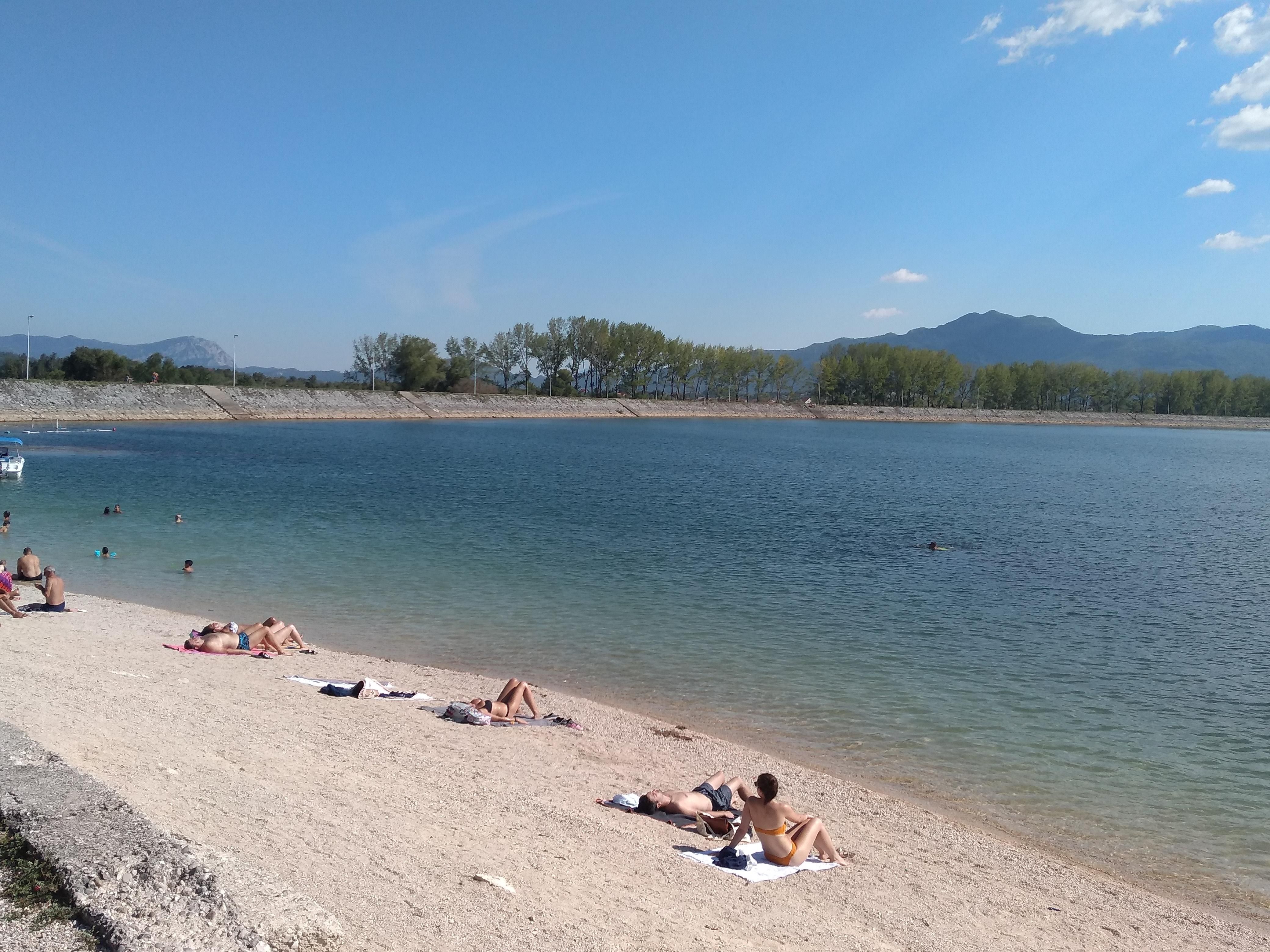 People sunbathing on the sandy beach of the popular Lake Krupac near Nikšić, Montenegro.