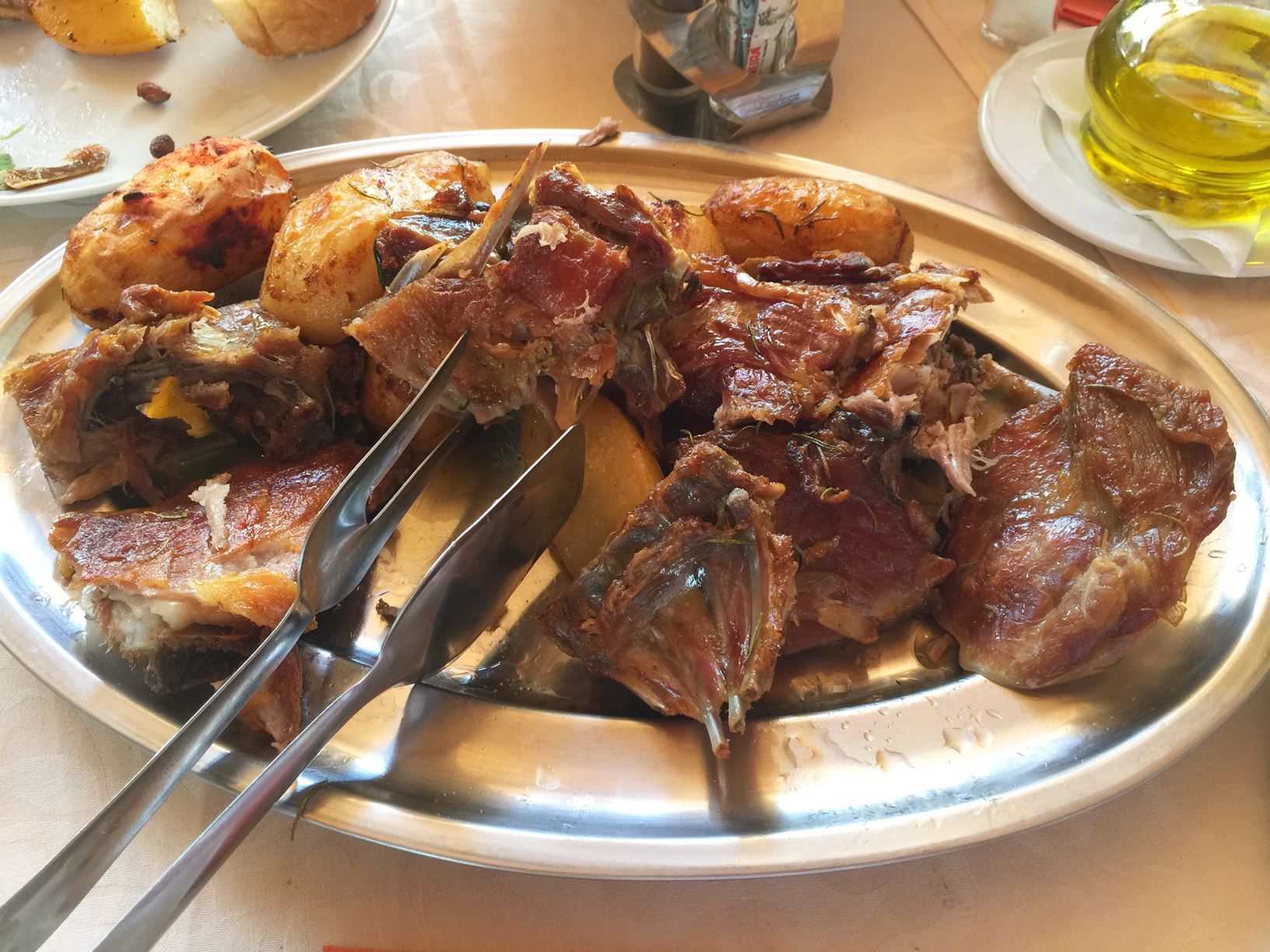 A large metal platter filled with delicious, traditionally roasted lamb and potatoes ('meso ispod sača').