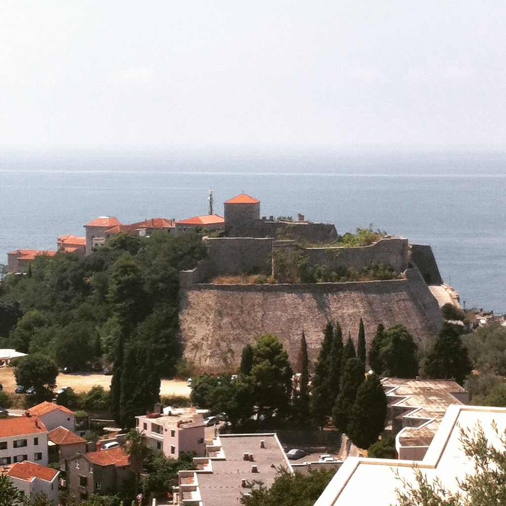 The massive defensive walls of Ulcinj's historic Old Town, with the blue sea in the background.