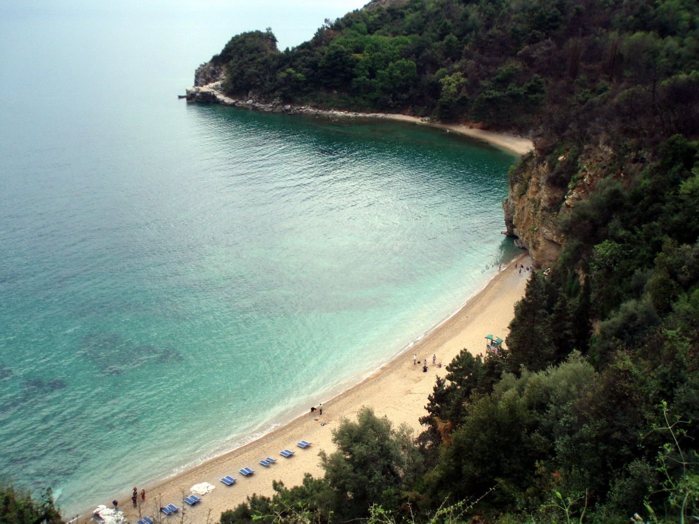 An aerial view of the beautiful cove of Mogren Beach, with its sandy shore and calm turquoise sea.
