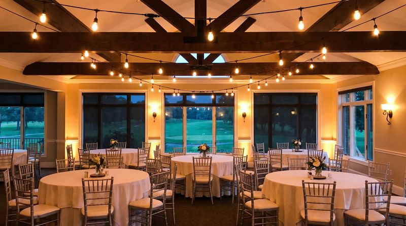 An upscale country club banquet room set up for a reunion with round tables and string lights