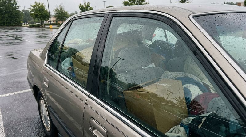 The back seat of a car packed with boxes and belongings seen through the window on an overcast morning
